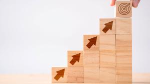 Close up hand arranging wood blocks with arrows
