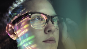 Individual wearing glasses with lines of code reflecting onto their face
